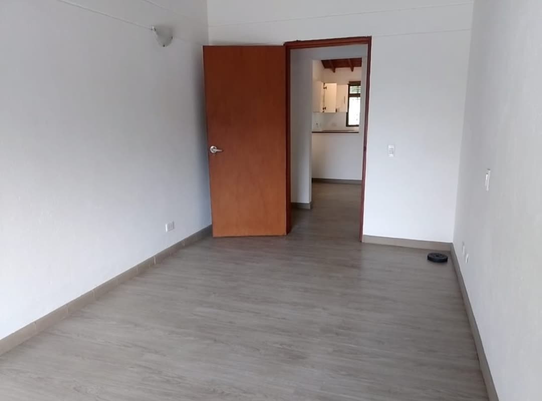 Habitación con piso laminado y acceso a la cocina